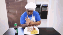 a man wearing a chef 's hat and apron looks at a plate of food with a bottle of coke on the table