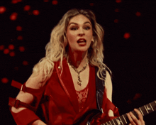 a woman in a red dress is playing a guitar with the letter h on the neck