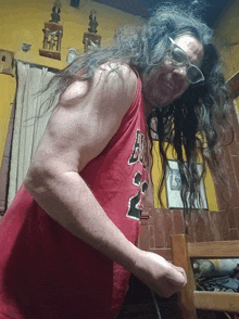 a man with long hair and glasses is wearing a red chicago bulls tank top