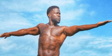 a shirtless man is standing with his arms outstretched against a blue sky .