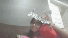 a girl wearing glasses and a red hat holds up a sign that says anaya