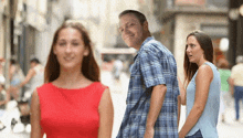 a man in a plaid shirt is walking down a street with a woman in a red dress .