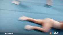 a blurry picture of a person laying on a blue surface with the nbc logo on the bottom