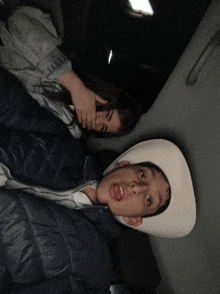 a boy wearing a cowboy hat is sticking out his tongue next to a woman