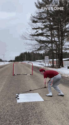 a man is playing a game of ice hockey on the side of the road with the words people are awesome above him