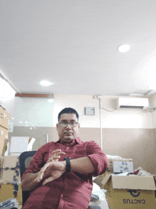 a man in a red shirt is sitting in front of a cardboard box that says cactus