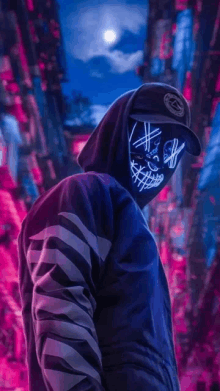 a man wearing a glow in the dark mask and a hoodie is standing in front of a city at night .