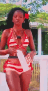 a woman in a red and white striped bikini is standing on a balcony .