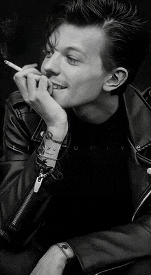 a man wearing a leather jacket is smoking a cigarette .