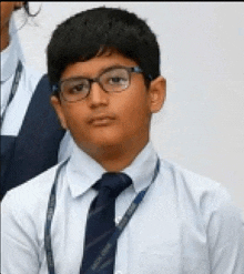 a young boy wearing glasses and a tie is standing in front of a group of people .