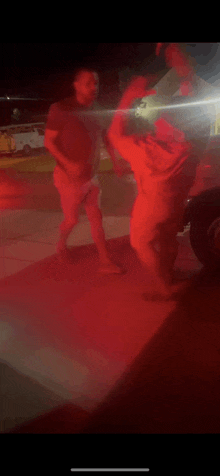 a couple of men are standing next to each other in a parking lot .