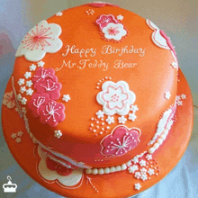 an orange birthday cake with pink and white flowers and the words happy birthday mr. teddy bear