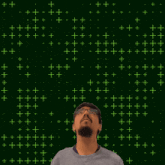a man with glasses stands in front of a green background with the number 18