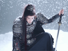 a man with long hair and armor holds a sword