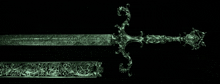 a green sword with a floral design on the handle and sheath on a black background