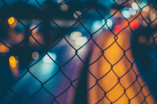 a chain link fence is surrounded by blurry lights