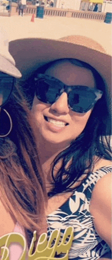 a woman wearing sunglasses and a hat smiles for a picture