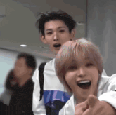 a group of young men are standing next to each other in a room and one of them is pointing at the camera .