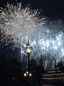 a street light is lit up in front of a large fireworks display