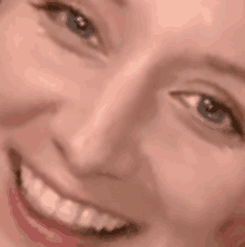a close up of a woman 's face smiling with her eyes closed .