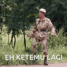 a man in a military uniform walking down a road with the words " eh ketemu lagi " written on the bottom