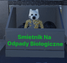 a white dog is sitting in a garbage can that says smietnik na odpady biologiczne