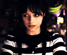 a woman wearing a black and white striped sweater with a button on the sleeve