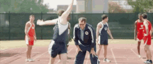 a group of men are playing a game of basketball on a track while a man is standing on the sidelines .