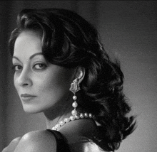 a black and white photo of a woman wearing pearls