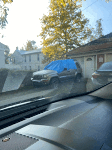 a car with a blue tarp covering the windshield