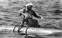 a black and white photo of a man in a boat with the letter a on his head