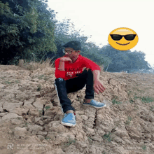 a young man wearing a red shirt that says black and white is sitting on a rock