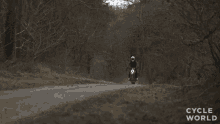 a person riding a motorcycle on a dirt road with the words cycle world visible