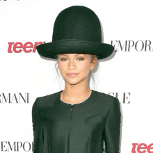 a woman wearing a green top hat stands in front of a sign that says emporia