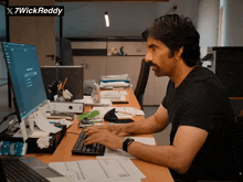 a man is typing on a keyboard in front of a computer and a sign that says x7wick reddy