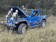 a blue jeep with the hood up and skeletons on the hood