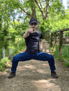 a man wearing sunglasses and a hat is squatting down and pointing