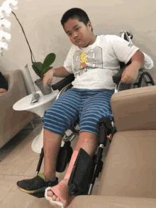 a boy in a wheelchair with a bart simpson shirt