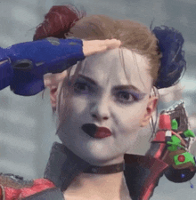 a close up of harley quinn 's face with a blue glove on her hand