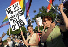 a woman holding a sign that says " we the people that means all of us "