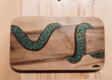 a painting of a snake is on a wooden cutting board