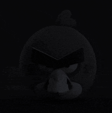 a black angry bird is sitting in the dark looking angry