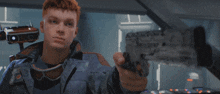 a man with red hair is holding a gun with the letter x on it