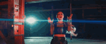 a woman in a black crop top is standing in a dark room