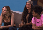 three women are sitting next to each other and one is wearing glasses