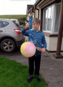 a boy is holding a balloon in front of a car