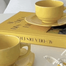 two yellow cups are sitting on top of a book