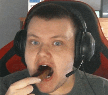 a man wearing headphones is eating something with his tongue out