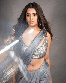 a woman wearing a gray saree and a silver sequined crop top