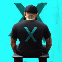 a man wearing a black shirt with the letter x on it